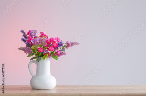beautiful flowers in white jug on wooden shelf