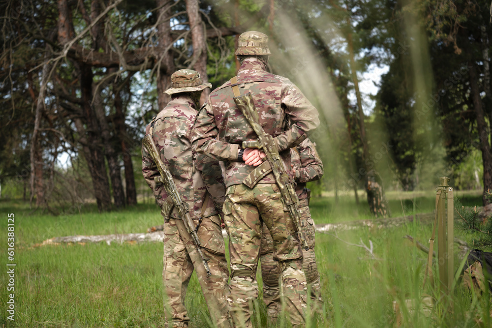 Squad of Four Fully Equipped Soldiers in Camouflage in the Forest.