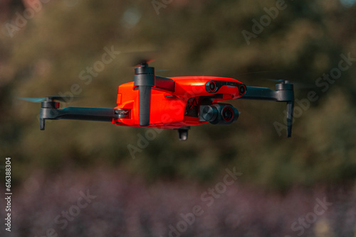 An orange, four-engined drone in flight.