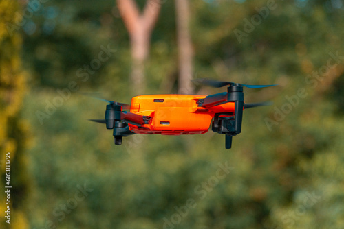 An orange, four-engined drone in flight.