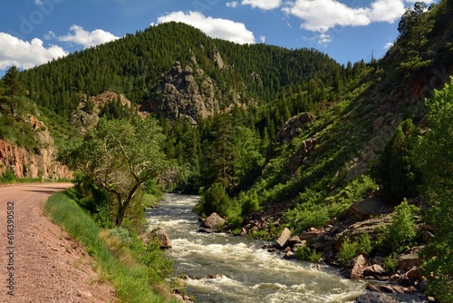 cycling trail, granite peaks and rapids on  in  the south platte river on a sunny  summer day  in  waterton canyon, littleton,  colorado