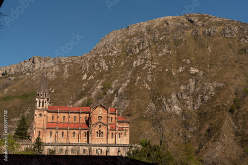 Panoramic view of the tourist basilica of Santa Mar  a la Real de Covadonga on a sunny day with clear skies  built between large rocky mountains  in the picos de europa  asturias.