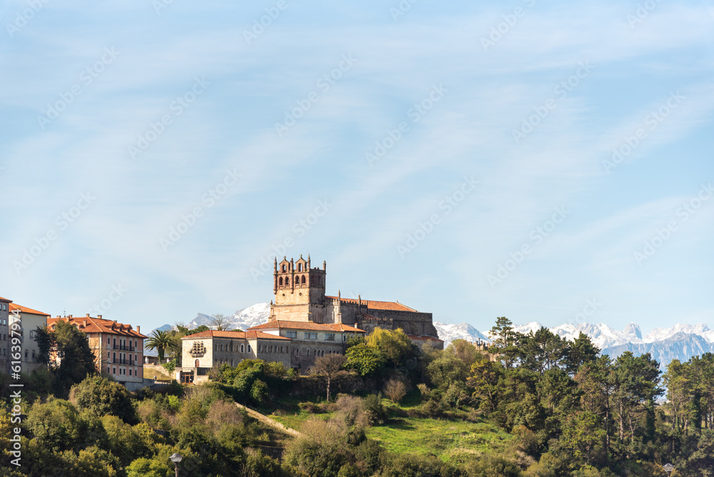Panoramic view of the medieval castle of the tourist village of San Vicente de la Barquera in Cantabria surrounded by an impressive natural landscape with the snow-capped Picos de Europa 