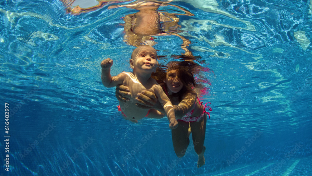 Funny photo of  happy active family young mother with active baby diving in swimming pool with fun jump deep down underwater.