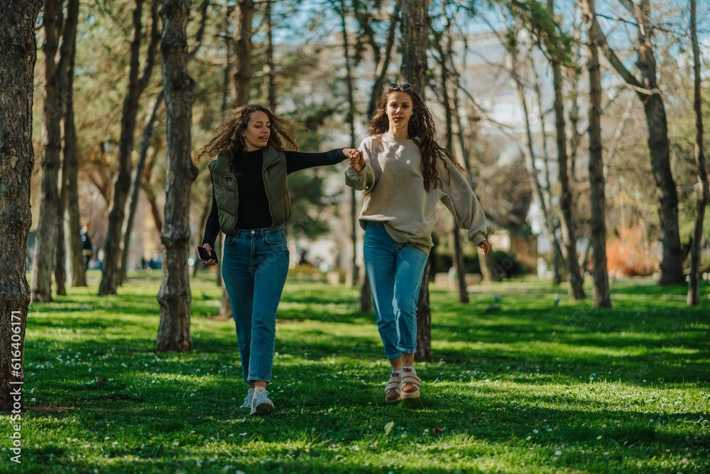 Front view shot of two lovely girls dancing while walking. They are holding their hands Front view shot of two lovely girls dancing while walking. They are holding their hands