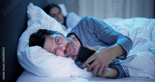 Young Man Using Cellphone While Her Wife Sitting On Bed photo