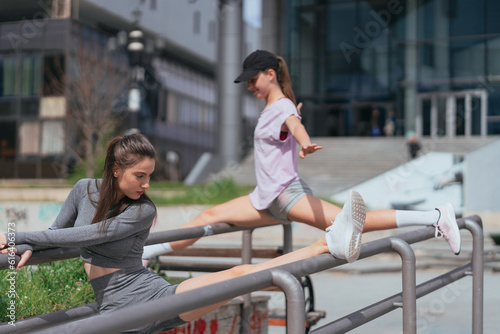 Two attractive sportsgirls exercising on metal fence photo