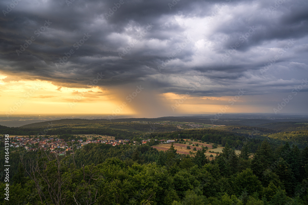 A summer thunderstorm with heavy rain moves over the city of Karlsruhe during the golden hour
