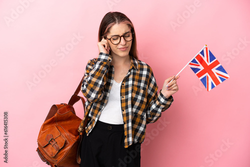 Young hispanic woman holding an United Kingdom flag isolated on pink background frustrated and covering ears