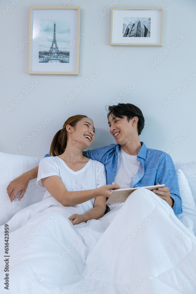 Couple playing in bed at home, hugging soft pillow, nose touching relaxed at home on bed