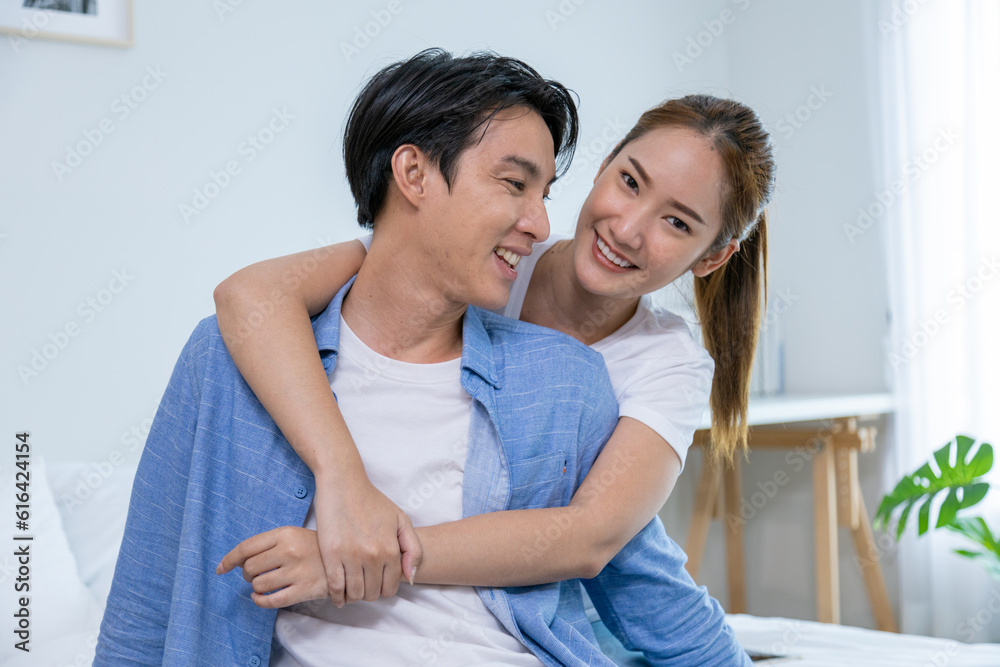 Couple playing in bed at home, hugging soft pillow, nose touching relaxed at home on bed Couple playing in bed at home, hugging soft pillow, nose touching relaxed at home on bed