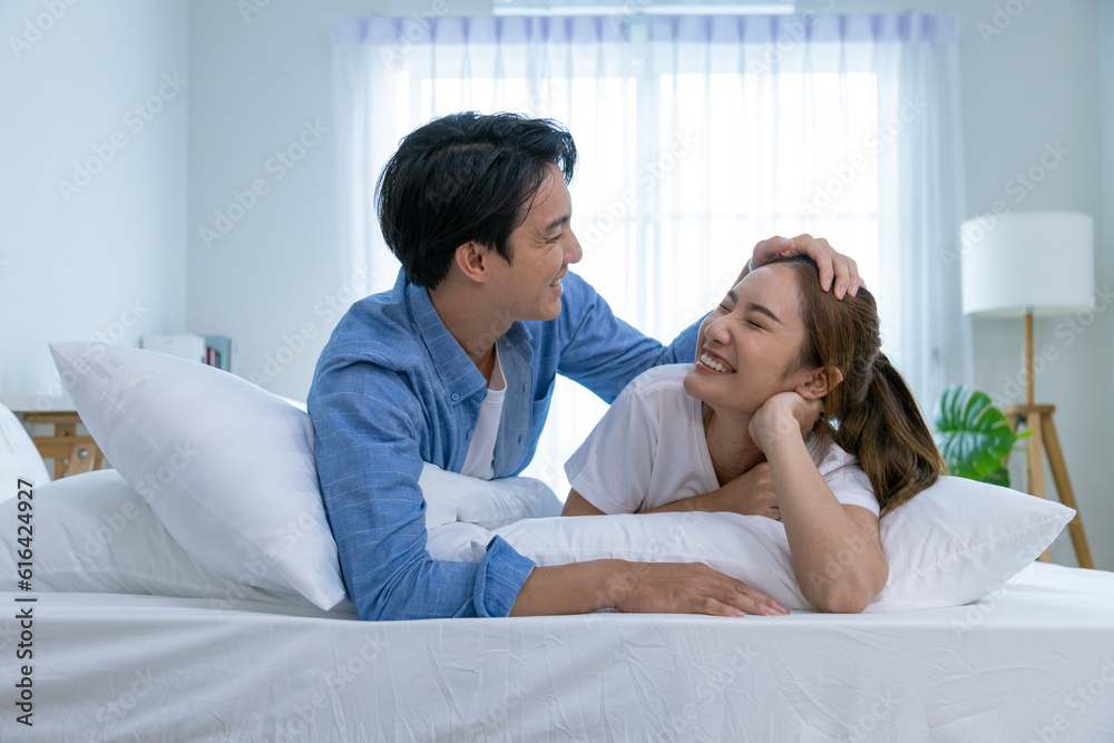 Couple playing in bed at home, hugging soft pillow, nose touching relaxed at home on bed Couple playing in bed at home, hugging soft pillow, nose touching relaxed at home on bed