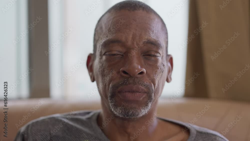 Close-up face of a middle-aged black man looking at camera with a serious expression, person changes emotion