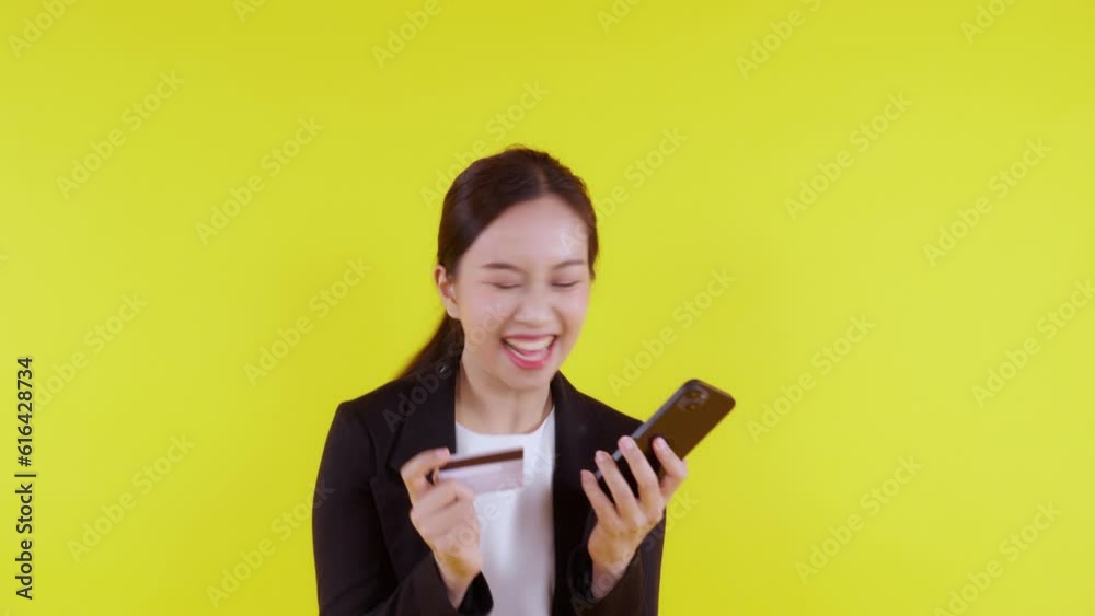 Portrait young asian business woman hold credit card and looking smart phone for shopping online isolated yellow background, businesswoman looking debit card and smartphone, financial concept. Portrait young asian business woman hold credit card and looking smart phone for shopping online isolated yellow background, businesswoman looking debit card and smartphone, financial concept.