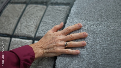 Fotografie Closeup of mature womans hand moving across carpet or rug samples in a hardware store