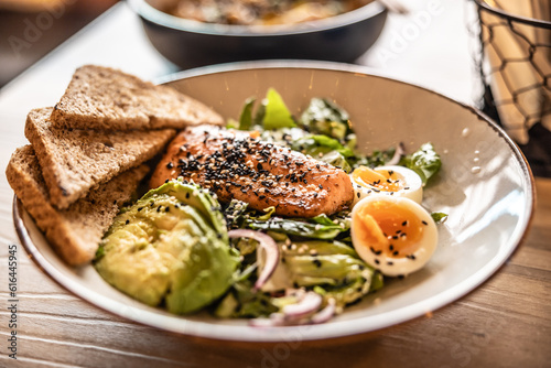 Healthy leaf salad prepared with avocado, eggs, sesame and grilled salmon