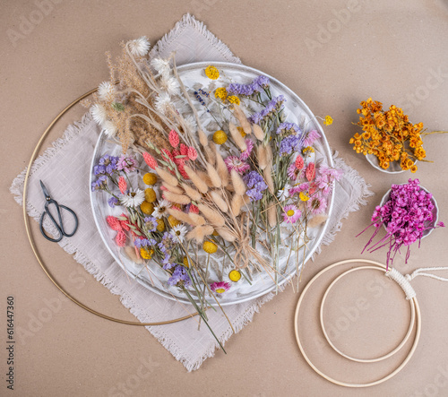 Farbenfrohe Trockenblumen auf einem Teller, getrocknete Blumen wie Lagurus, Strandflieder, Hirse, Craspedia, Pampasgras, Phalaris und Strohblumen
 photo