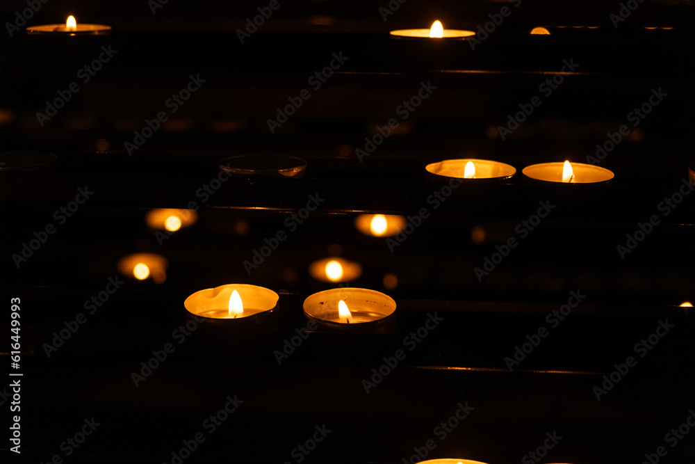 A lot of burning candles in the temple in the dark. The concept of religion, prayer and God. A lot of burning candles in the temple in the dark. The concept of religion, prayer and God.