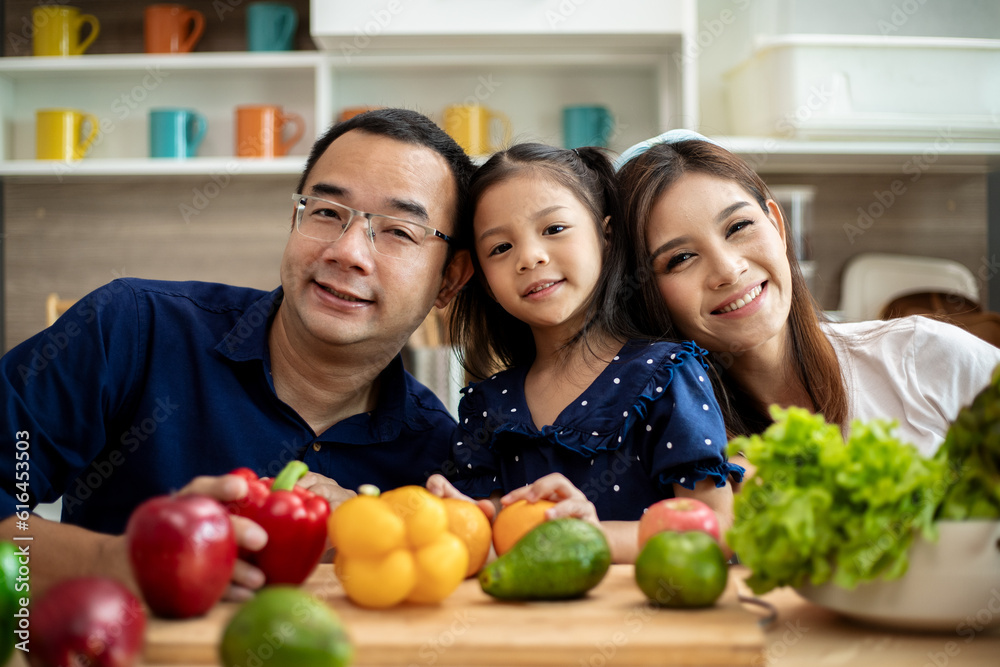 Young Asian family are preparing vegetables for the breakfast, fruits chili on table in the kitchen which Excited smiling and felling happy time.
