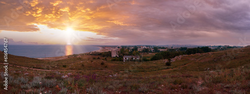 Dramatic sunset sea and evening town on horizon, Crimea, Ukraine.