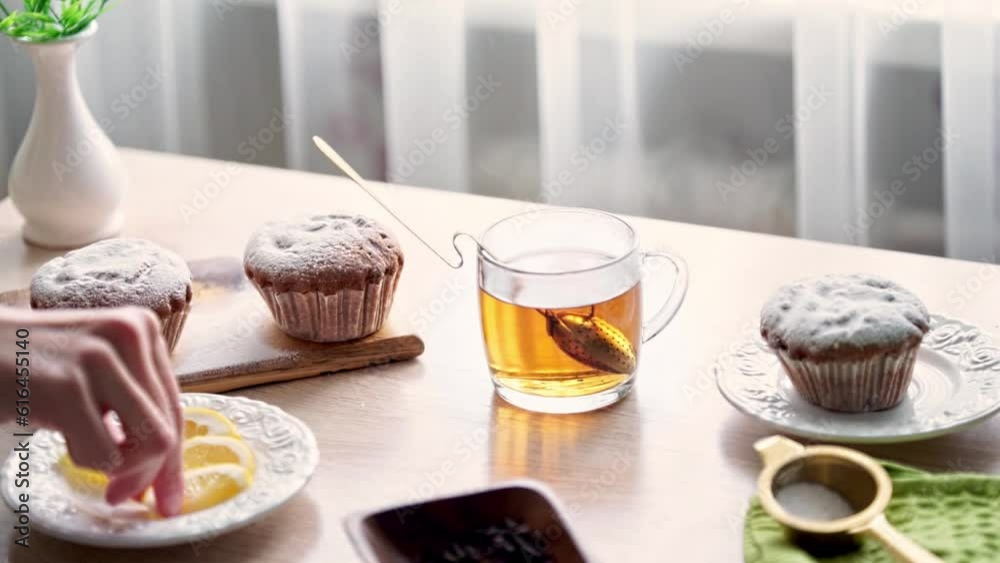 a woman puts a lemon in a cup of hot tea a woman puts a lemon in a cup of hot tea
