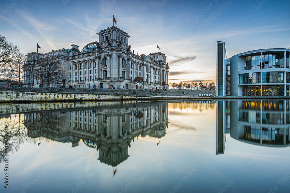 Government district in Berlin on a winter day. Reichstag and Paul Löbe House in the evening at sunset. River Spree with reflection on water surface of government buildings. Clouds in the sky