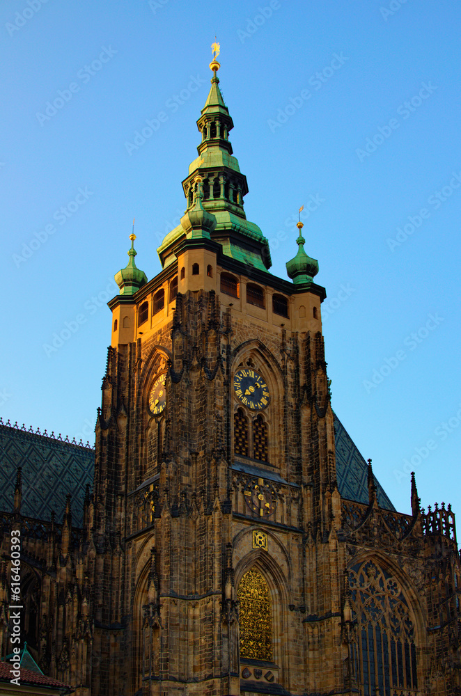 Tower with golden clock against blue sky. Saint Vitus Cathedral, Wenceslas and Adalbert Cathedral in Hradcany. Famous touristic place and romantic travel destination in Prague, Czech Republic