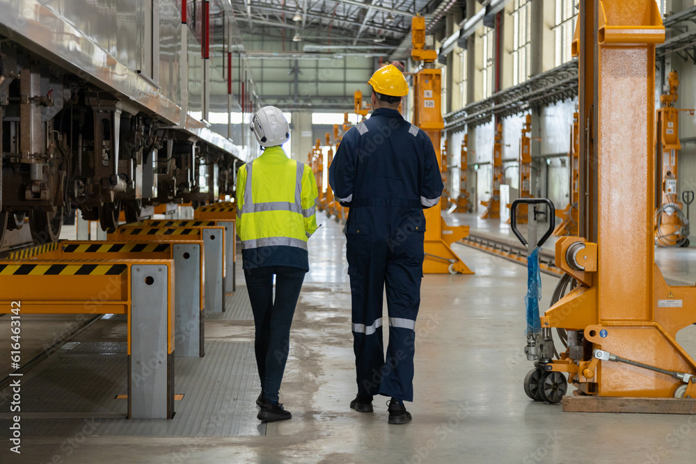 Two professional engineers check mechanical check undercarriage of lifted electric train and maintenance of public transport trains in Asia Two professional engineers check mechanical check undercarriage of lifted electric train and maintenance of public transport trains in Asia