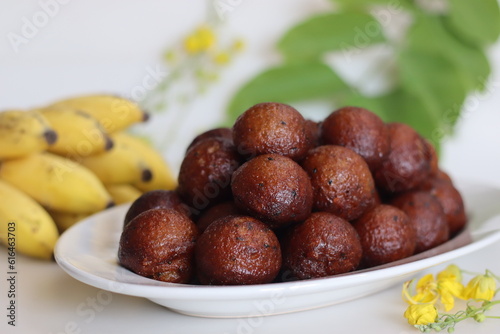 Unniyappam. Delicious sweet rice fritters made with a batter of rice, banana, jaggery, ghee fried coconut pieces, black sesame seeds and flavored with cardamom photo