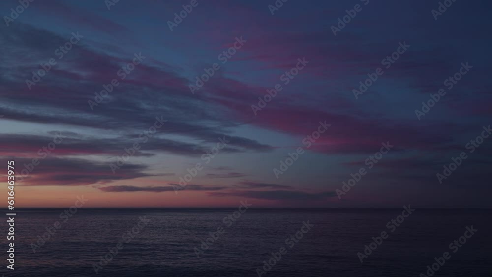Beautiful sunset with purple clouds and flying birds over the sea