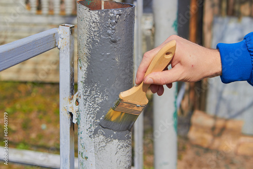 painting a fence post with a brush,Anticorrosive painting of a metal fence post, hand with a brush, corrosion protection