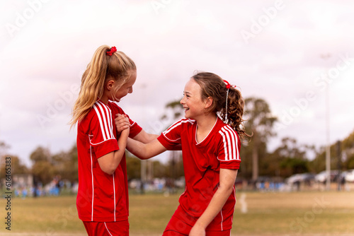 Two young female football players encouraging one another and smiling