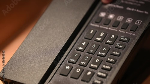 Close up of hotel guest pick up the phone holding and dialing phone numbers to hotel room services. Hotel phone services concept.