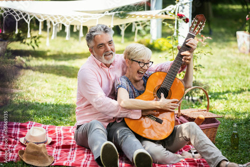 Foto Elderly couple playing the guitar on grass