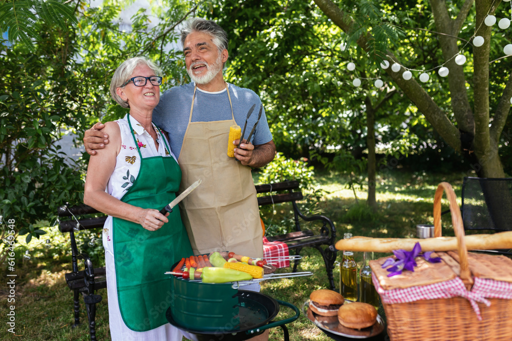 Obraz premium Elderly couple celebrate the 4th of July in their backyard by making barbeque
