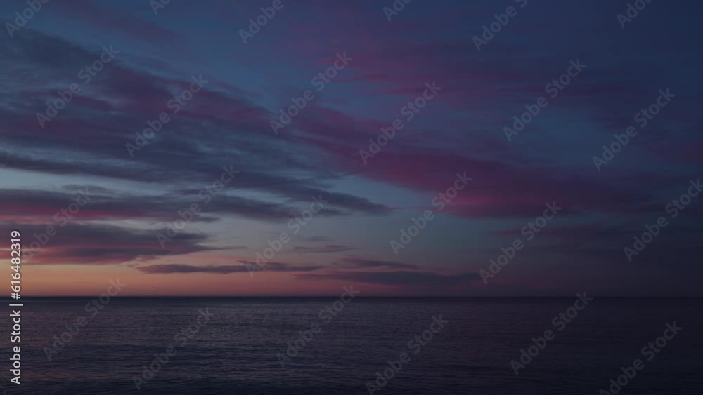 Beautiful sunset zoom shot with purple clouds and flying birds over the sea Beautiful sunset zoom shot with purple clouds and flying birds over the sea