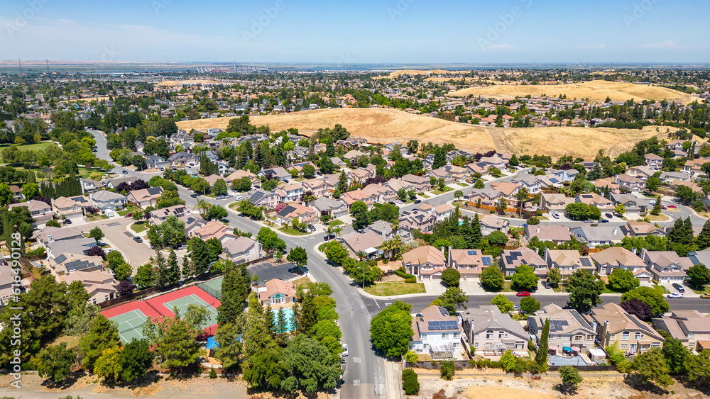 Aerial images over a community in Antioch, California with houses, cars, streets and trees. With a blue sky and room for text