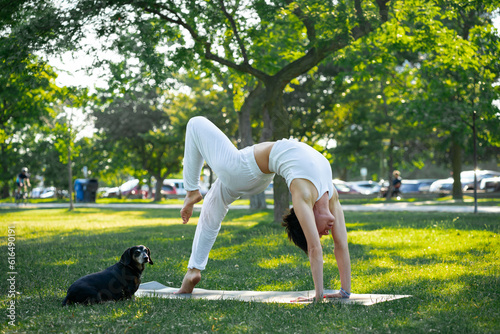 Sporty young Caucasian woman doing yoga with her dog practice concept of healthy life and natural balance between body and mental development outside in the Park