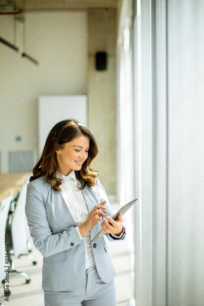 Young woman working on digital tablet by the office window Young woman working on digital tablet by the office window