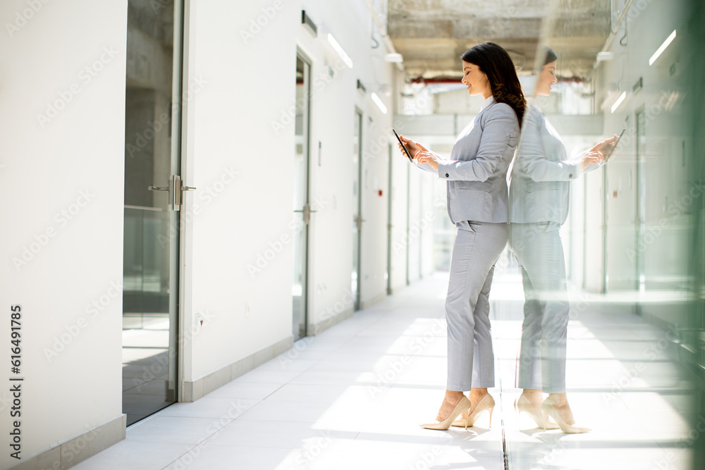 Young business woman using mobile phone in the office hallway