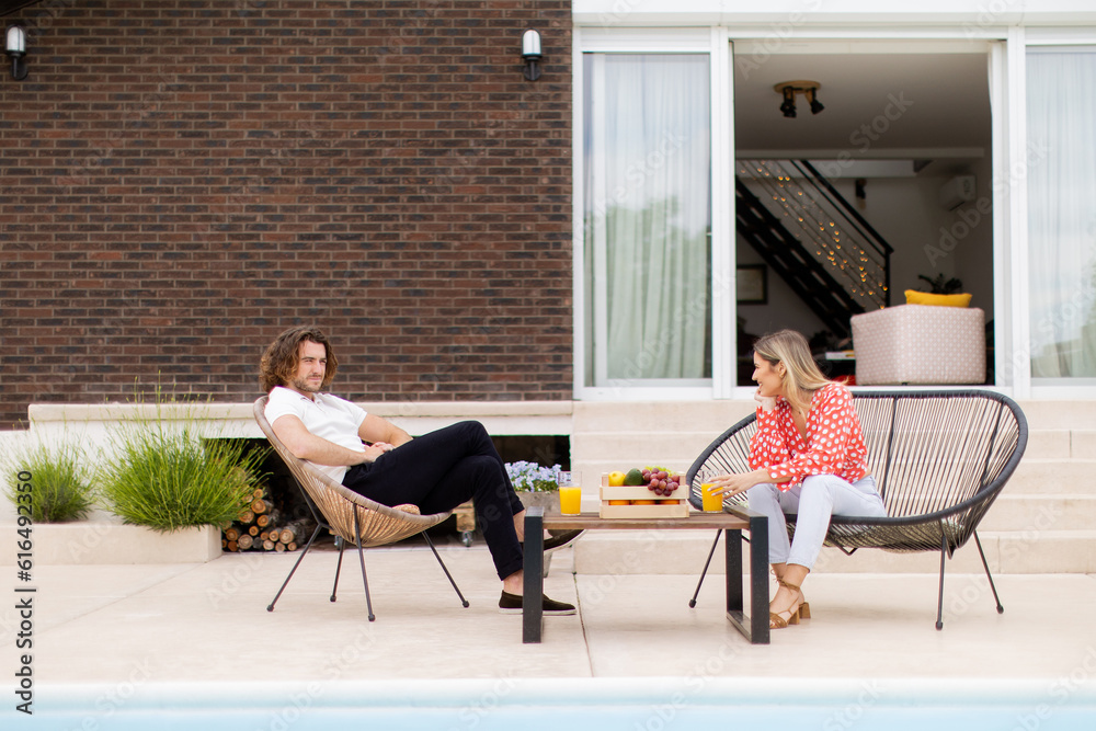 Young couple relaxing by the swimming pool in the house backyard Young couple relaxing by the swimming pool in the house backyard
