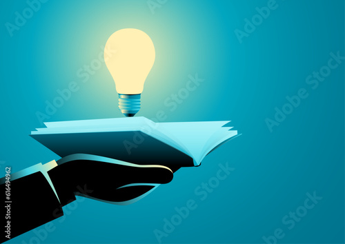 Businessman hand holding a book and light bulb, innovation, knowledge, idea and inspiration concept