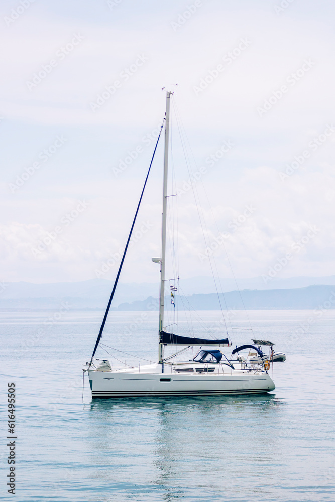 Recreational sailboat anchored off the coast during a cloudy day, adventure concept, travel, vertical shot.