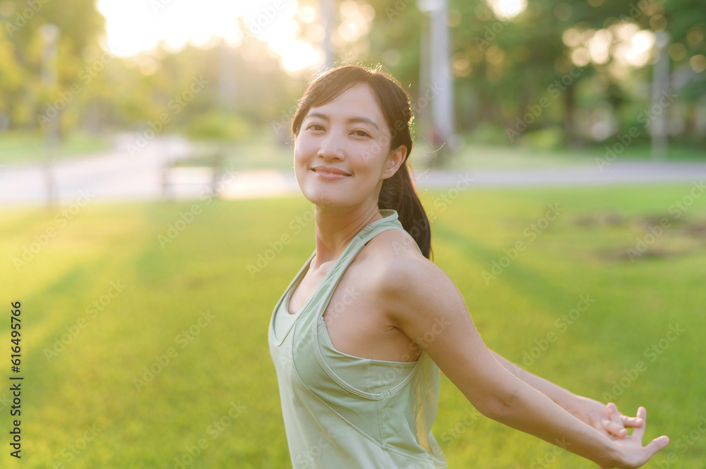 Female jogger. Fit young Asian woman with green sportswear breathing fresh air in park before running and enjoying a healthy outdoor. Fitness runner girl in public park. Wellness being concept Female jogger. Fit young Asian woman with green sportswear breathing fresh air in park before running and enjoying a healthy outdoor. Fitness runner girl in public park. Wellness being concept