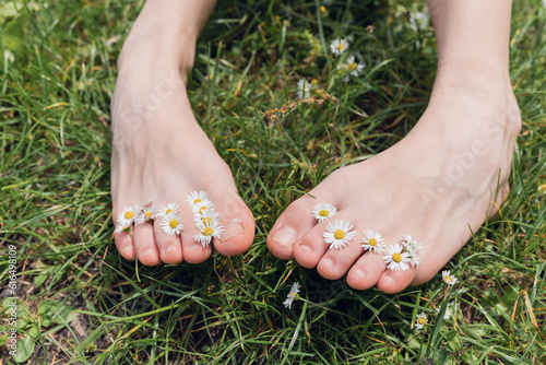 Bare feet young woman on grass with daisies