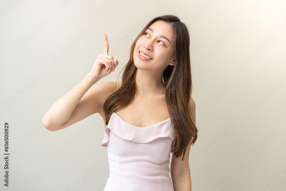 Smiling positive, attractive asian young woman, girl pointing finger, wearing beautiful pink dress with female brunette long hair feeling happy looking at camera standing isolated on white background Smiling positive, attractive asian young woman, girl pointing finger, wearing beautiful pink dress with female brunette long hair feeling happy looking at camera standing isolated on white background