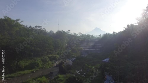 Aerial Grojogan Watu Purbo Sleman Yogyakarta Indonesia - Set of uniform cascades created by a dam with Mount Merapi and Merbabu on The Background photo