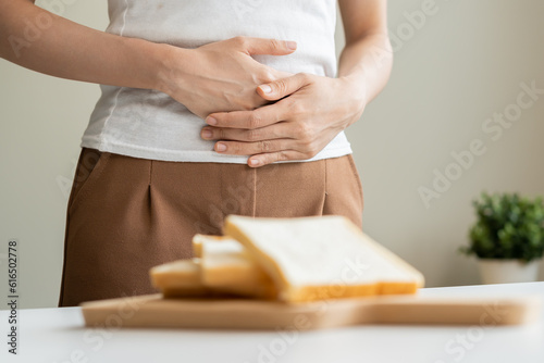 Gluten allergy, asian young woman hand push out, refusing to eat white bread slice on chopping board in food meal at home, girl having a stomach ache. Gluten intolerant and Gluten free diet concept.