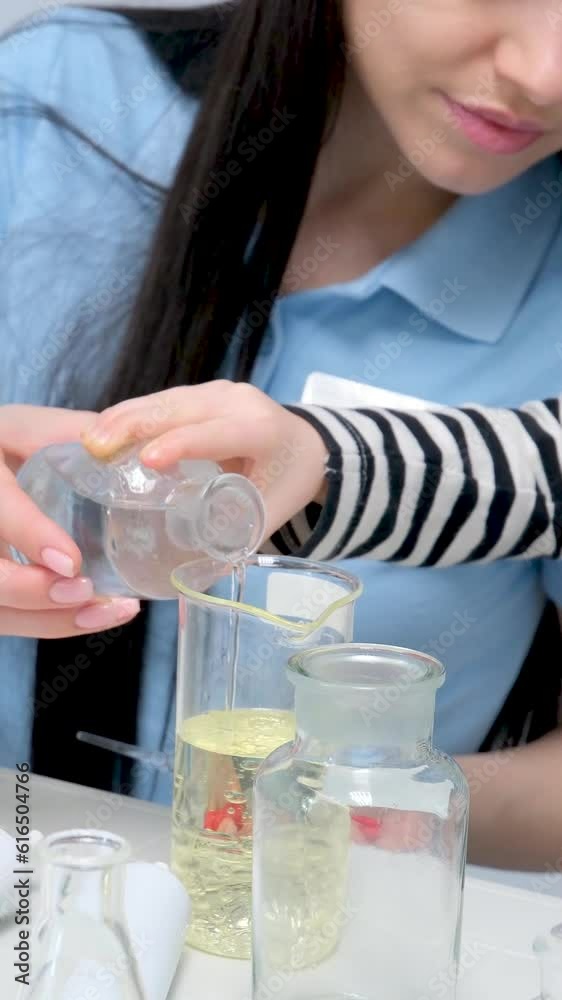 Young woman mixing liquids in test tube with multiethnic children watching, learning about science, chemistry. Asian school teacher and students in science class. High quality 4k footage Young woman mixing liquids in test tube with multiethnic children watching, learning about science, chemistry. Asian school teacher and students in science class. High quality 4k footage
