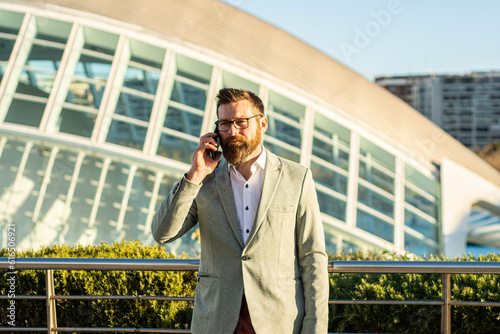 Portrait of young businessman telephoning with smartphone. Businessman with phone in an urban setting.